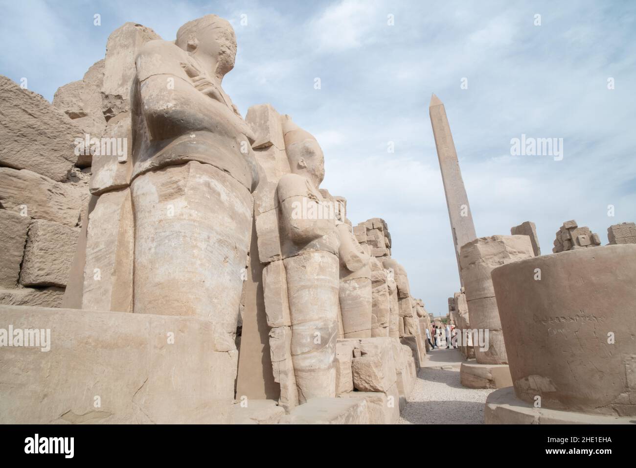 Statuen im Vordergrund und ein Obelisk im Hintergrund am Karnak-Tempel, einer archäologischen Stätte in Ägypten. Stockfoto