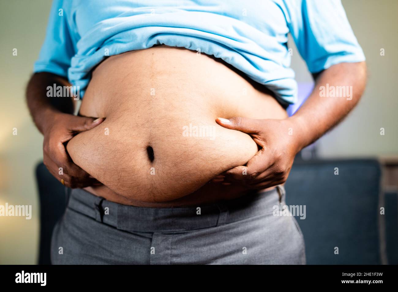 Unkenntlich Fat man Kontrolle durch Schütteln Bauchfett - Konzept der ungesunden Lebensweise, Messung von Übergewicht Körperfett Stockfoto