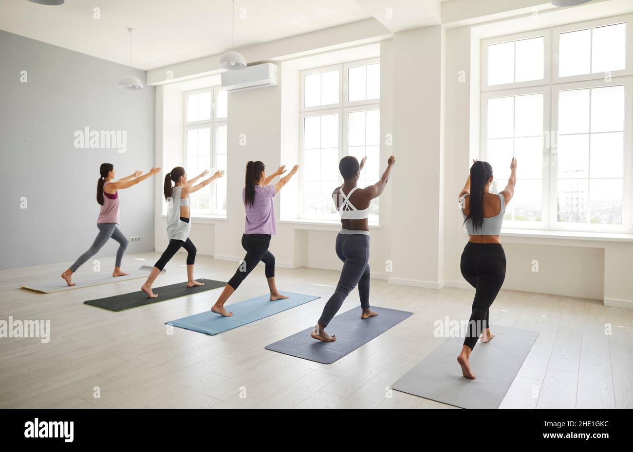 Verschiedene junge Frauen führen gemeinsam Pilates-Übungen in einem hellen, geräumigen Raum durch. Stockfoto