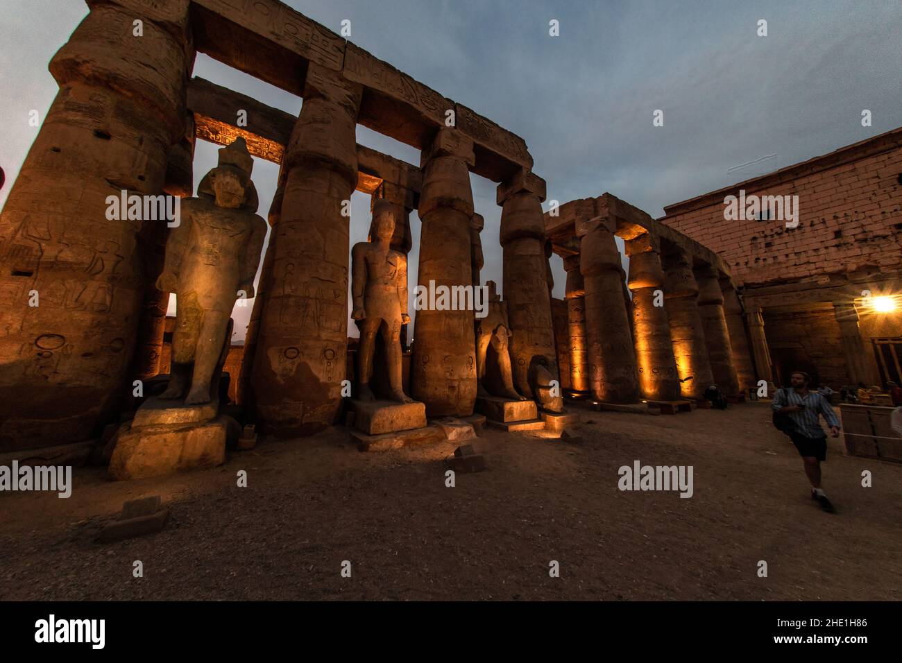 Statuen und Säulen im Luxor-Tempel in Ägypten, die am Abend durch Lichter beleuchtet werden, wenn die Dunkelheit fällt, was einen wunderschönen und dramatischen Effekt bewirkt. Stockfoto