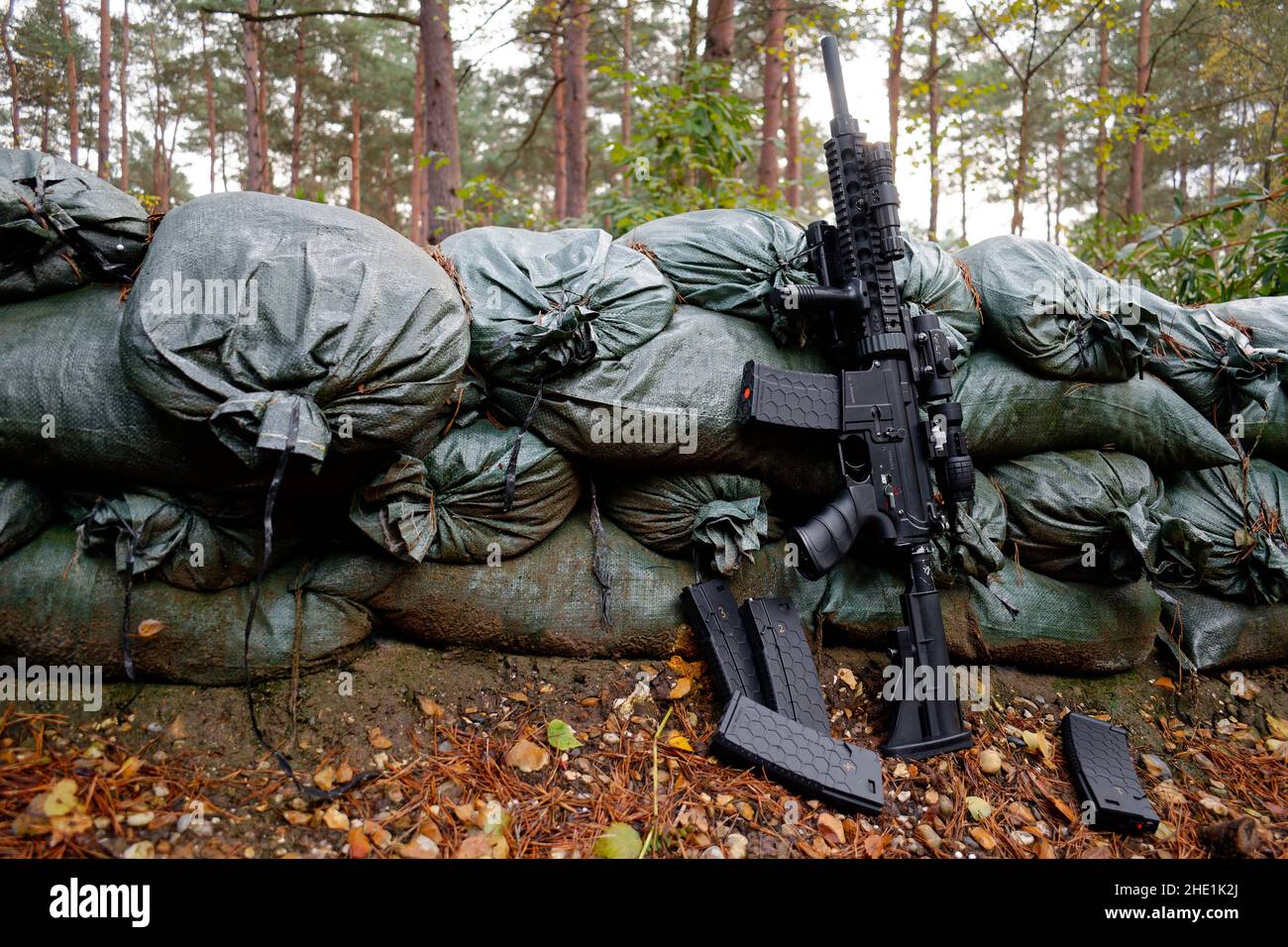 Airsoft Replik M4-M16 lehnt sich auf Sandsäcke um ein Foxhole. Stockfoto