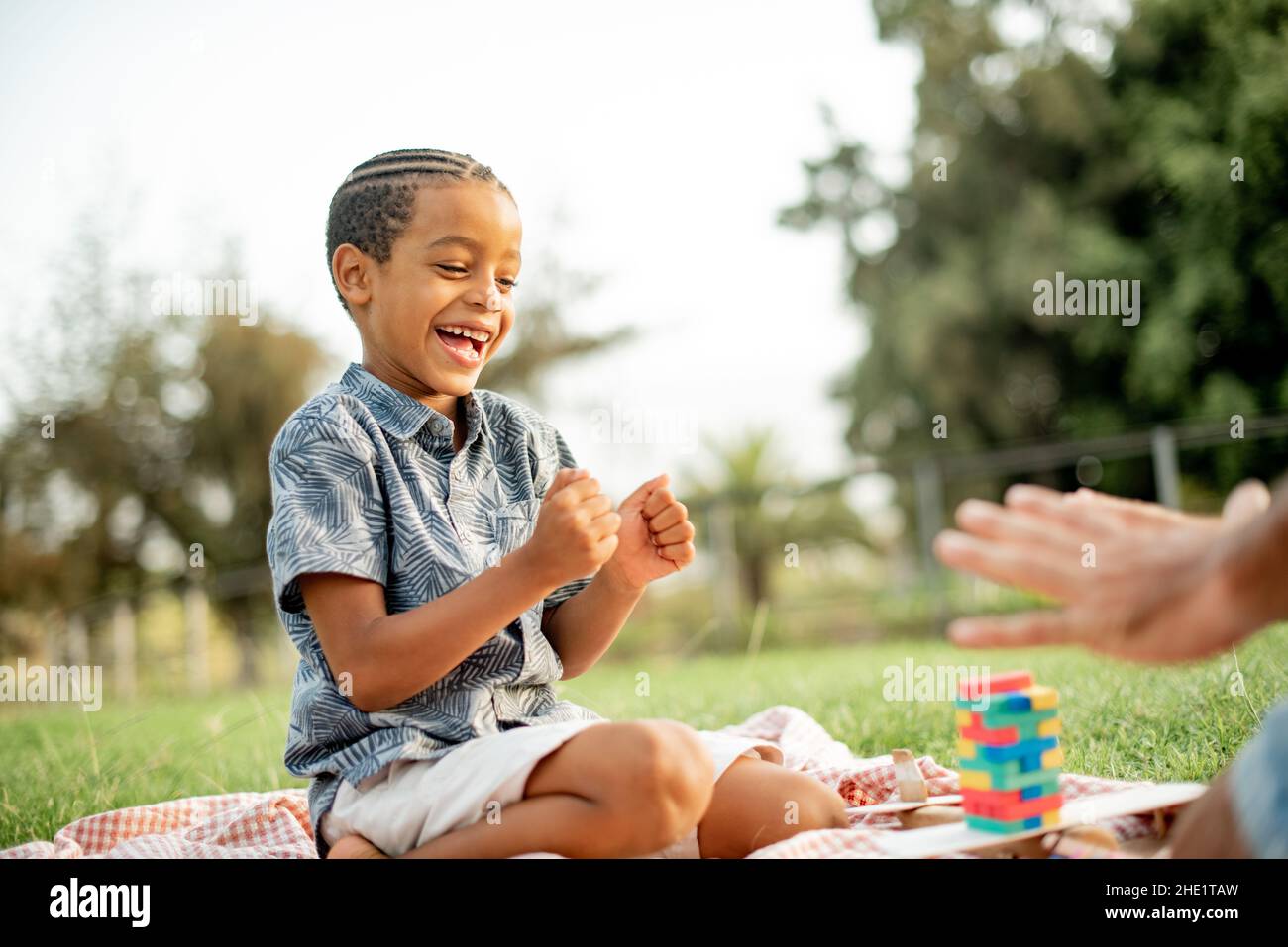 Content Black Kid feiert Sieg beim Brettspiel im Park Stockfoto