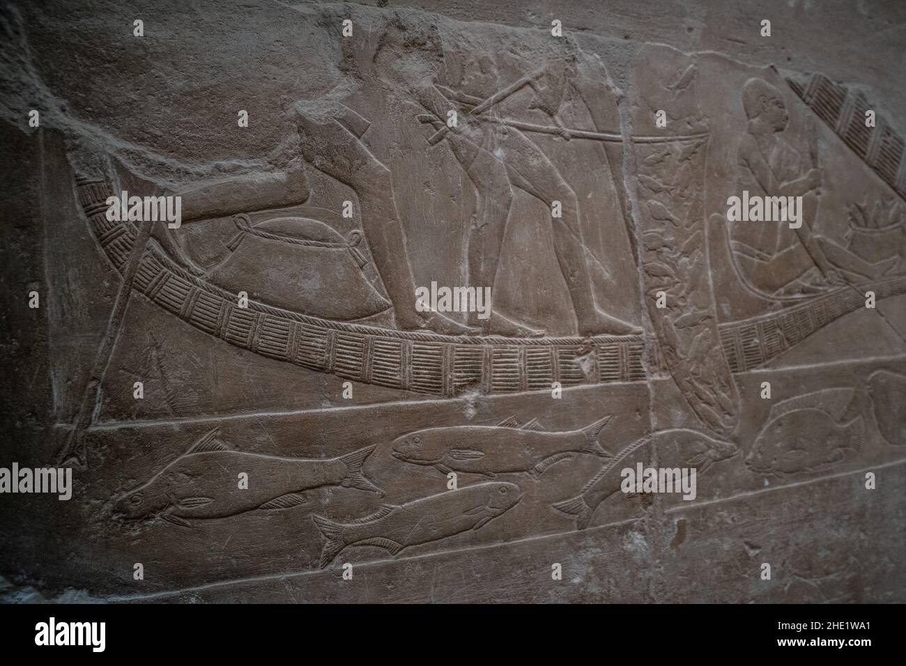 Eine alte Steinreliefskulptur an der Nekropole von Saqqara in Ägypten, die ein Boot und einen Fisch im Nil darstellt. Stockfoto