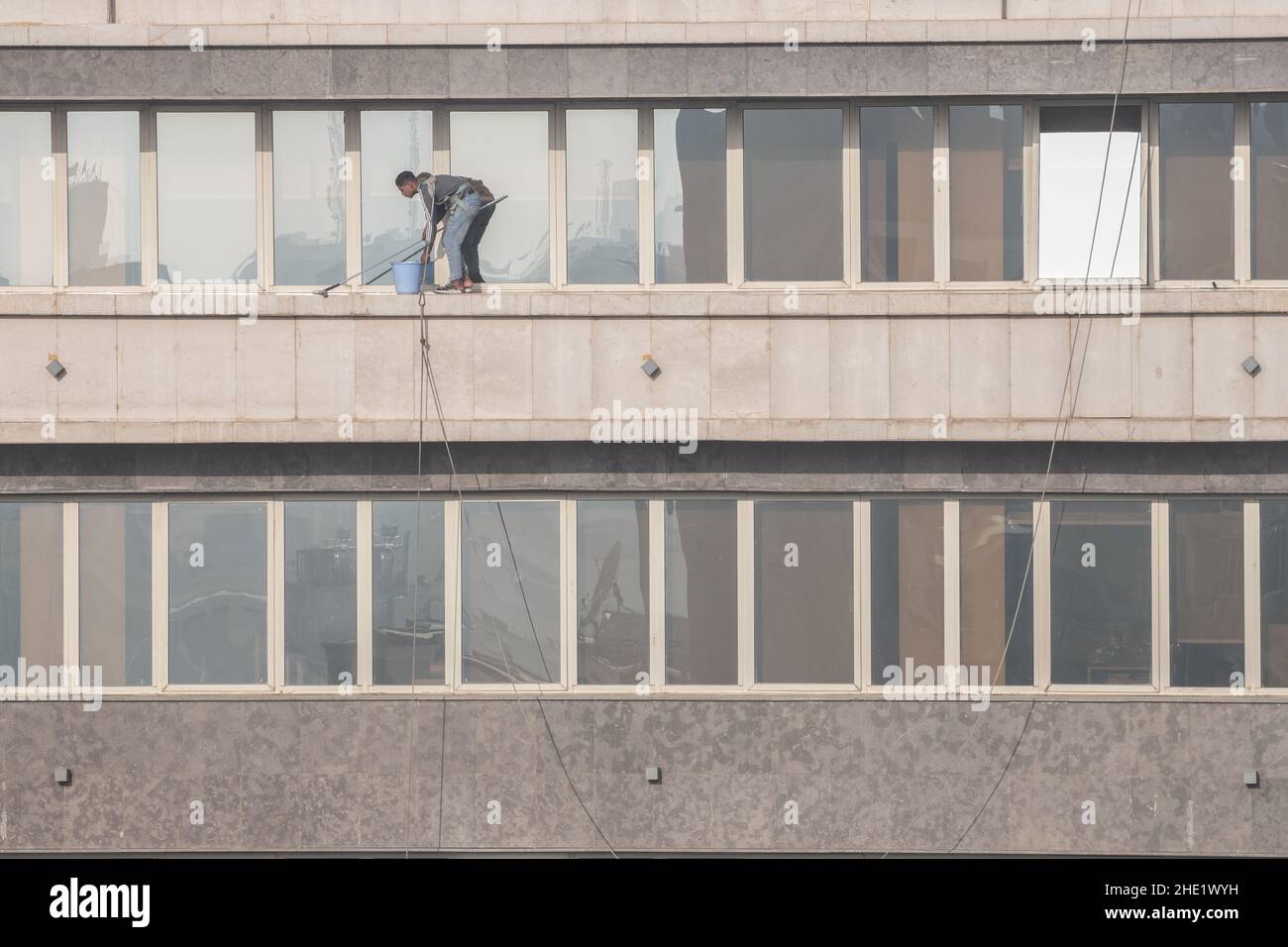 Eine Fensterwaschanlage in Kairo, Ägypten, arbeitet an der Reinigung des Glases eines Hochhauses viele Stockwerke hoch. Gefährliche Arbeiten mit minimaler Sicherheitsausrüstung. Stockfoto
