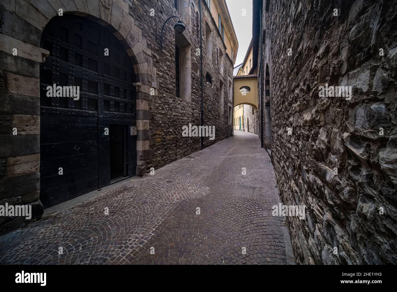 Dunkle, kleine mittelalterliche Gasse mit Kopfsteinpflaster und Steinmauern mitten in der Stadt. Stockfoto