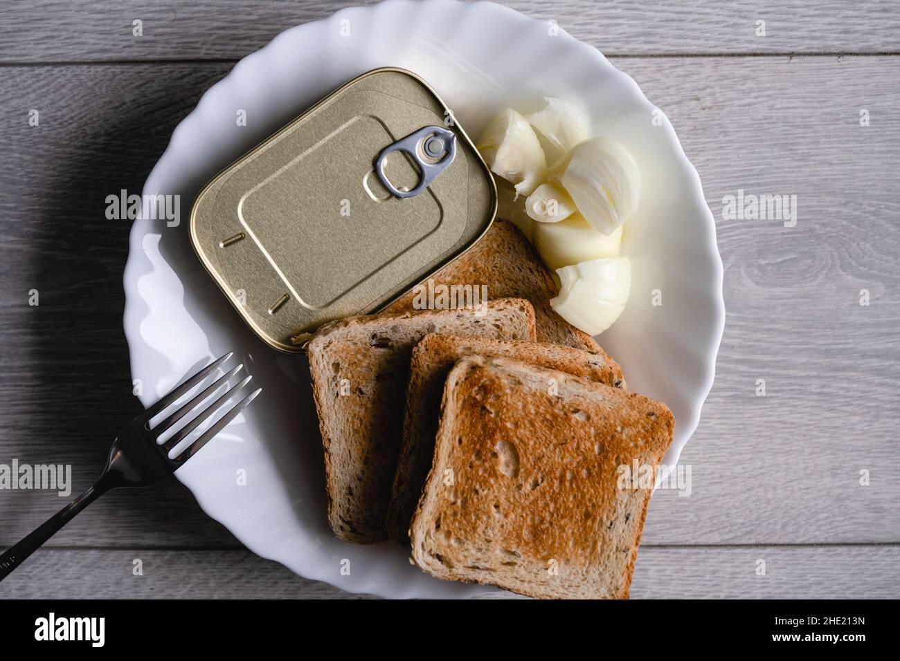 Nahaufnahme auf dem Teller mit getoastetem Brot gehackte Zwiebel und Dose mit Sardinen Fischfutter Fastenkonzept Stockfoto