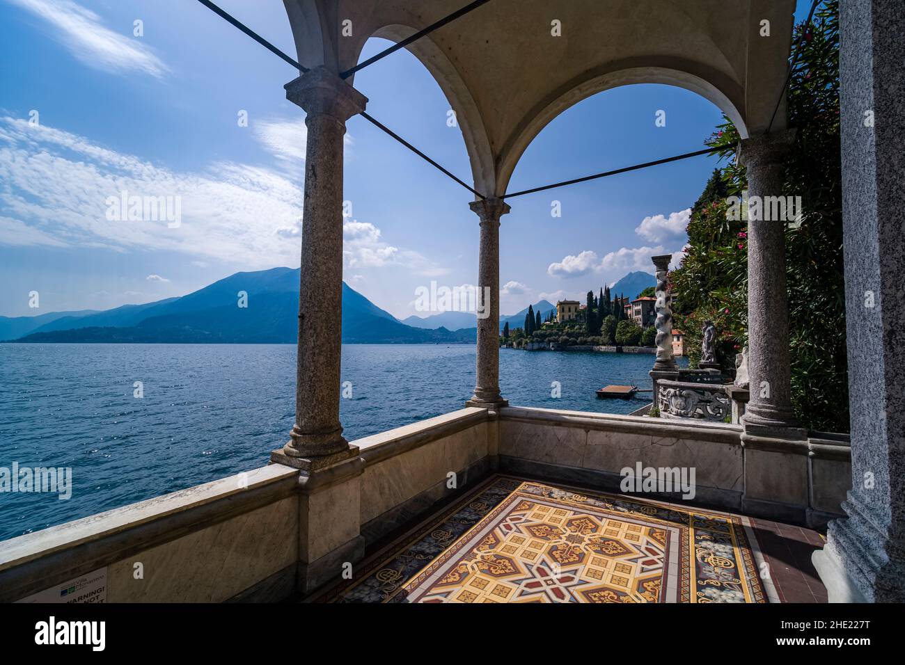 Blick auf den Comer See und die umliegenden Berge von den Arkaden des Giardino di Villa Monastero. Stockfoto