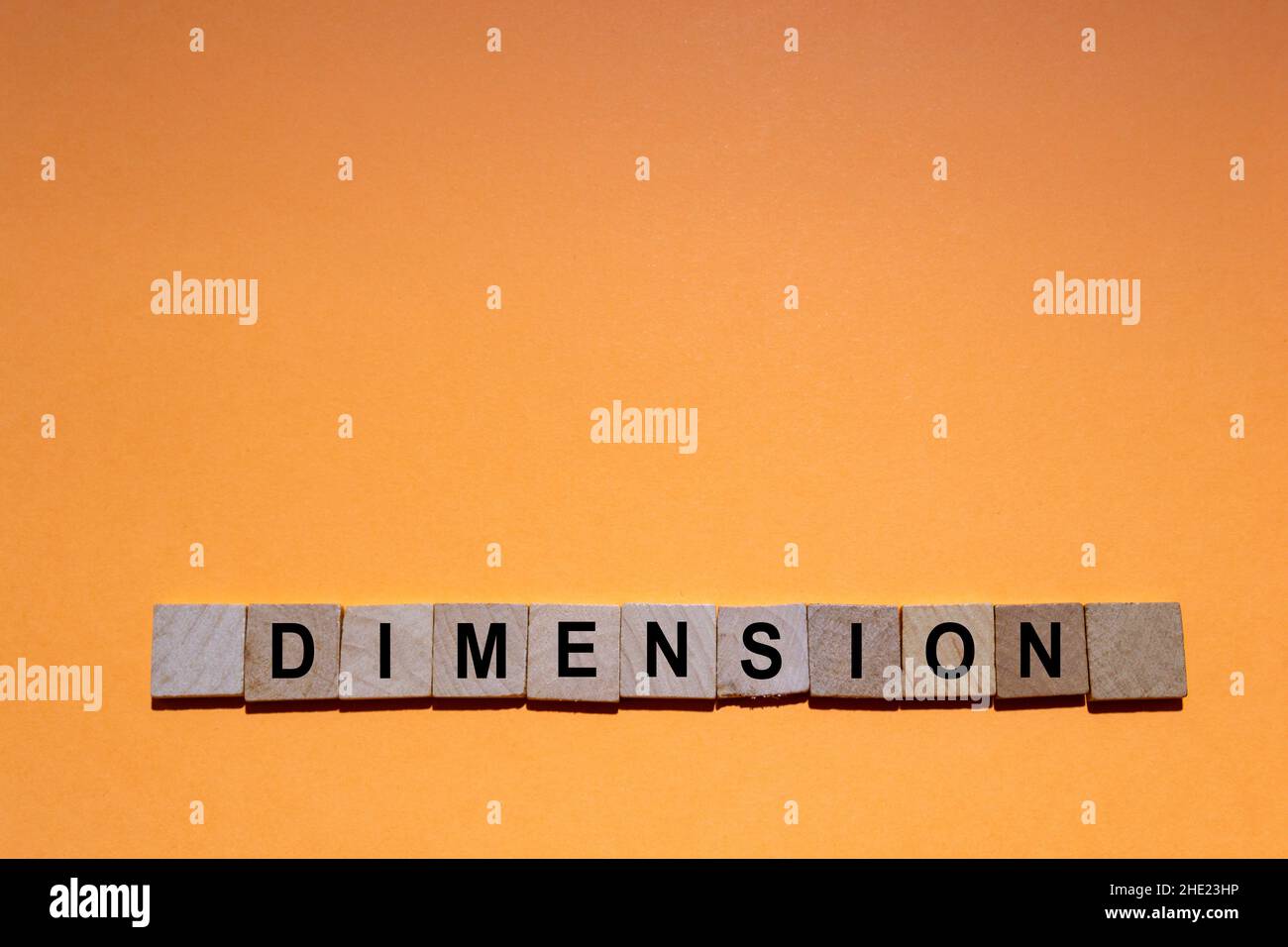 ABMESSUNGEN. Wort auf quadratischen Holzfliesen mit orangefarbenem Hintergrund geschrieben. Horizontale Fotografie. Stockfoto