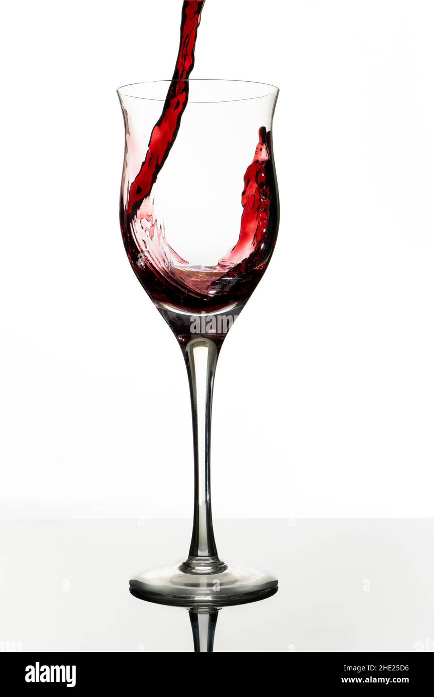 Serviert ein schönes Glas mit Rotwein. Weißer Hintergrund, Glasbecher. Eleganz, guter Geschmack, Stilkonzept. Stockfoto