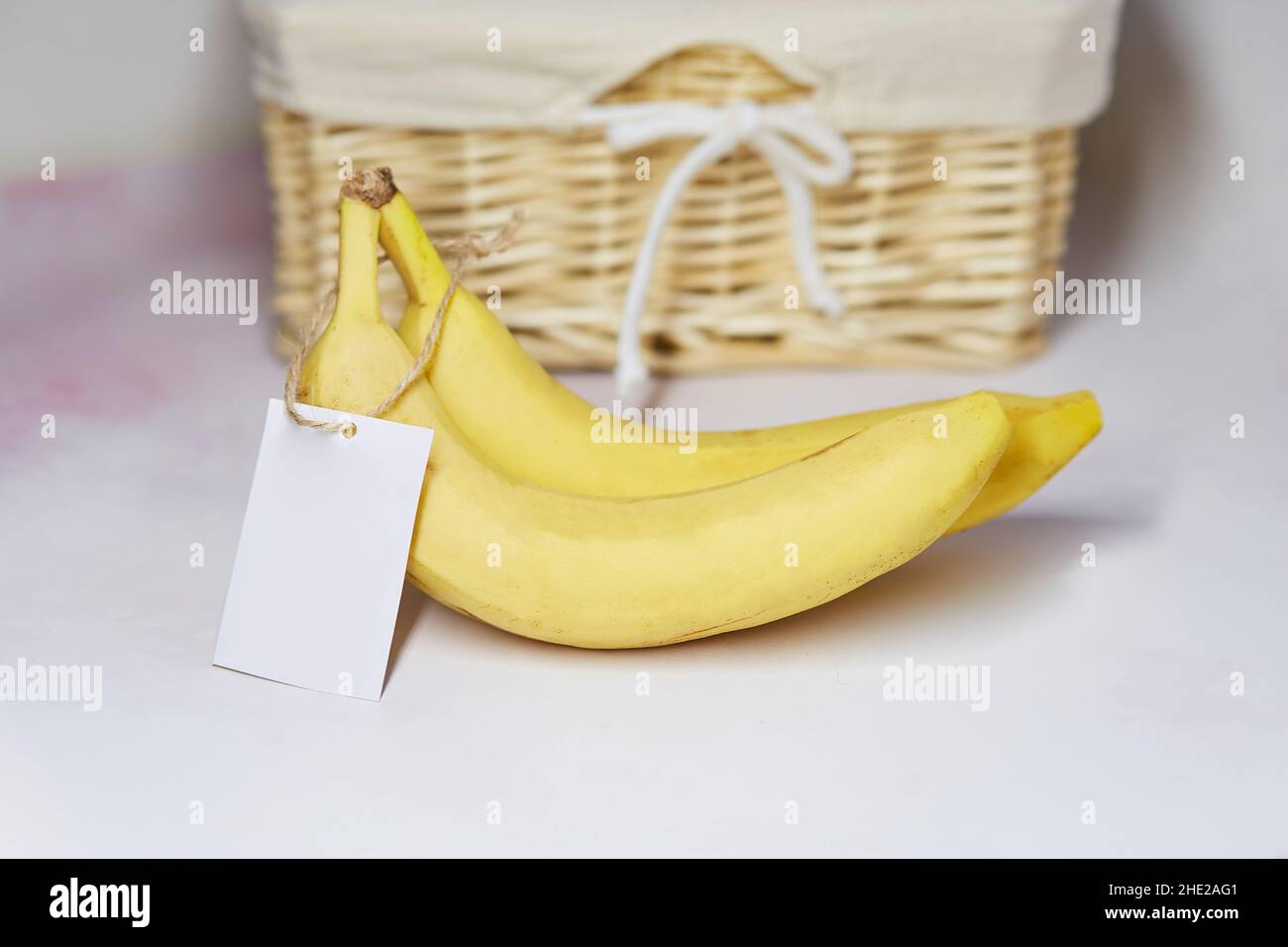 Mock-up-Etikett auf Bananen. Aufkleber Produkt für Text oder Preis. Korbkorb auf dem Hintergrund. Bio-Landwirtschaftsprodukte vom lokalen Markt. Speicherplatz kopieren Stockfoto