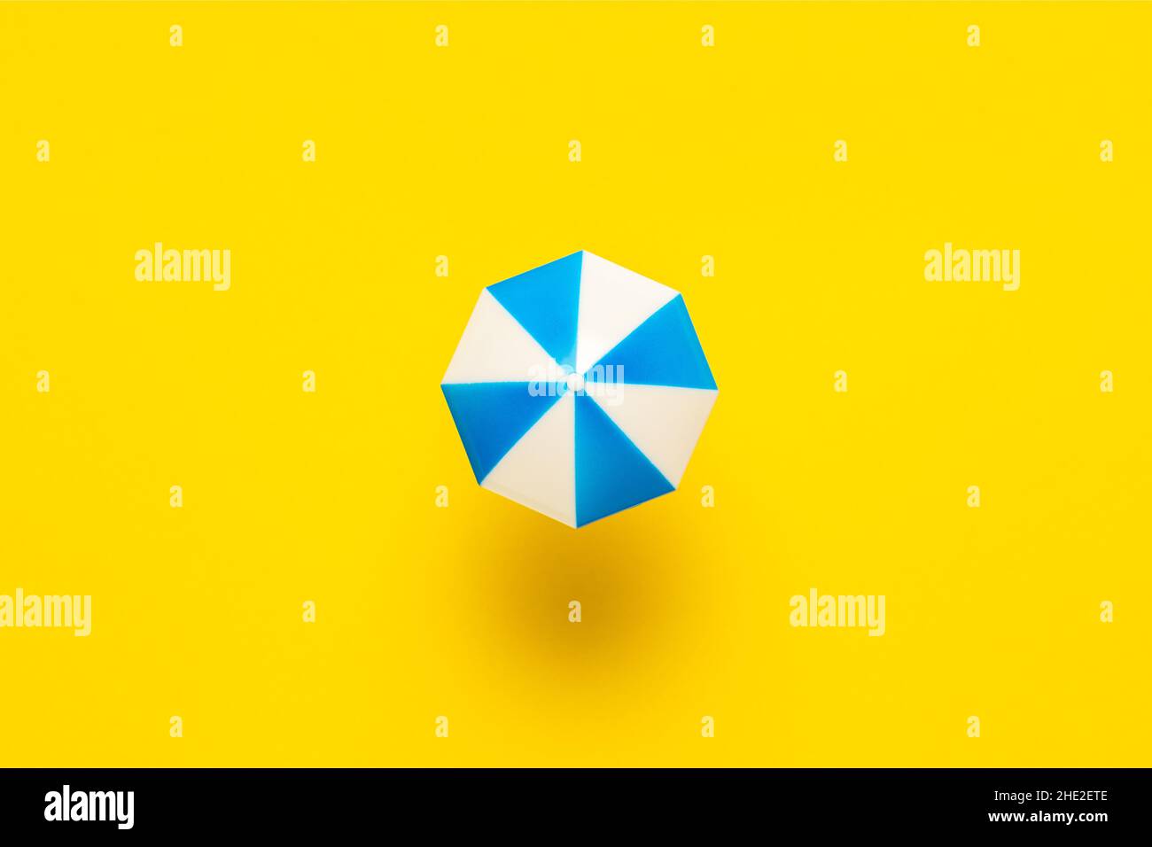 Minimales Strandkonzept mit Sonnenschirm auf gelbem Hintergrund. Flach lag Sommer Hintergrund. Stockfoto