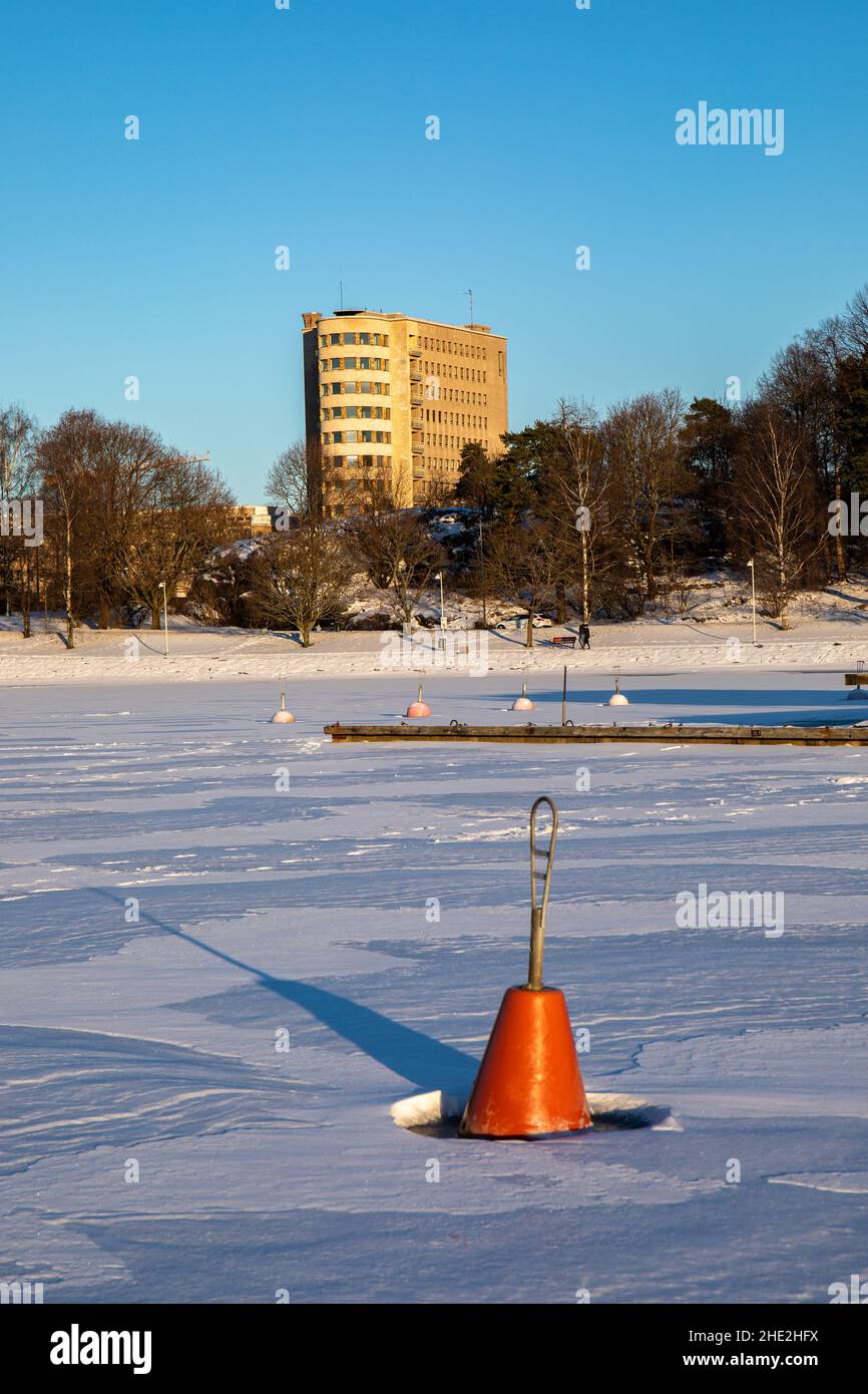 Ankerboje auf gefrorener Bucht mit Lastenlinna im Hintergrund in Helsinki, Finnland Stockfoto