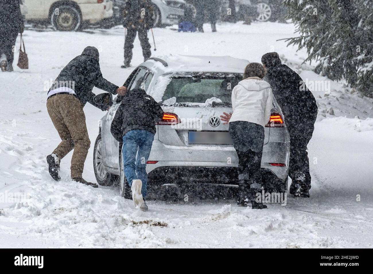 08. Januar 2022, Bayern, St. Englmar: Menschen, die von einem Skigebiet aus ein Auto auf einen schneebedeckten Parkplatz schieben. Foto: Armin Weigel/dpa Stockfoto