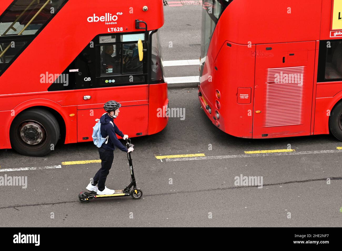 London, England - 2021. Juni: Luftaufnahme einer Person, die auf einem Elektroroller an Bussen vorbeifährt, auf einer Straße im Zentrum von London Stockfoto