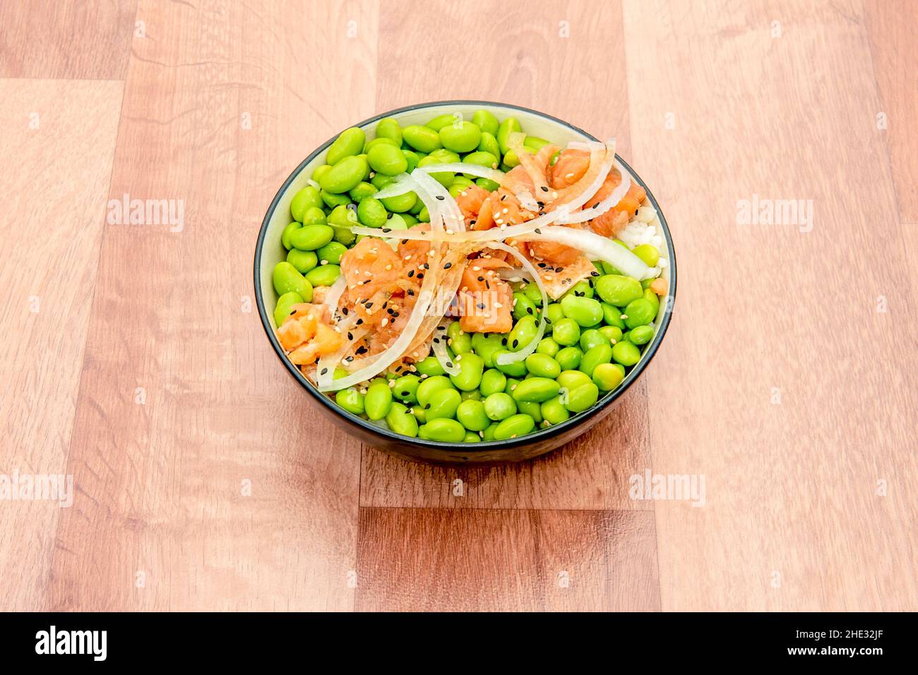 Unreife Sojaschoten, in Salzwasser gekocht und ganz mit mariniertem Lachs und roher Zwiebel über gekochtem weißen Reis serviert Stockfoto