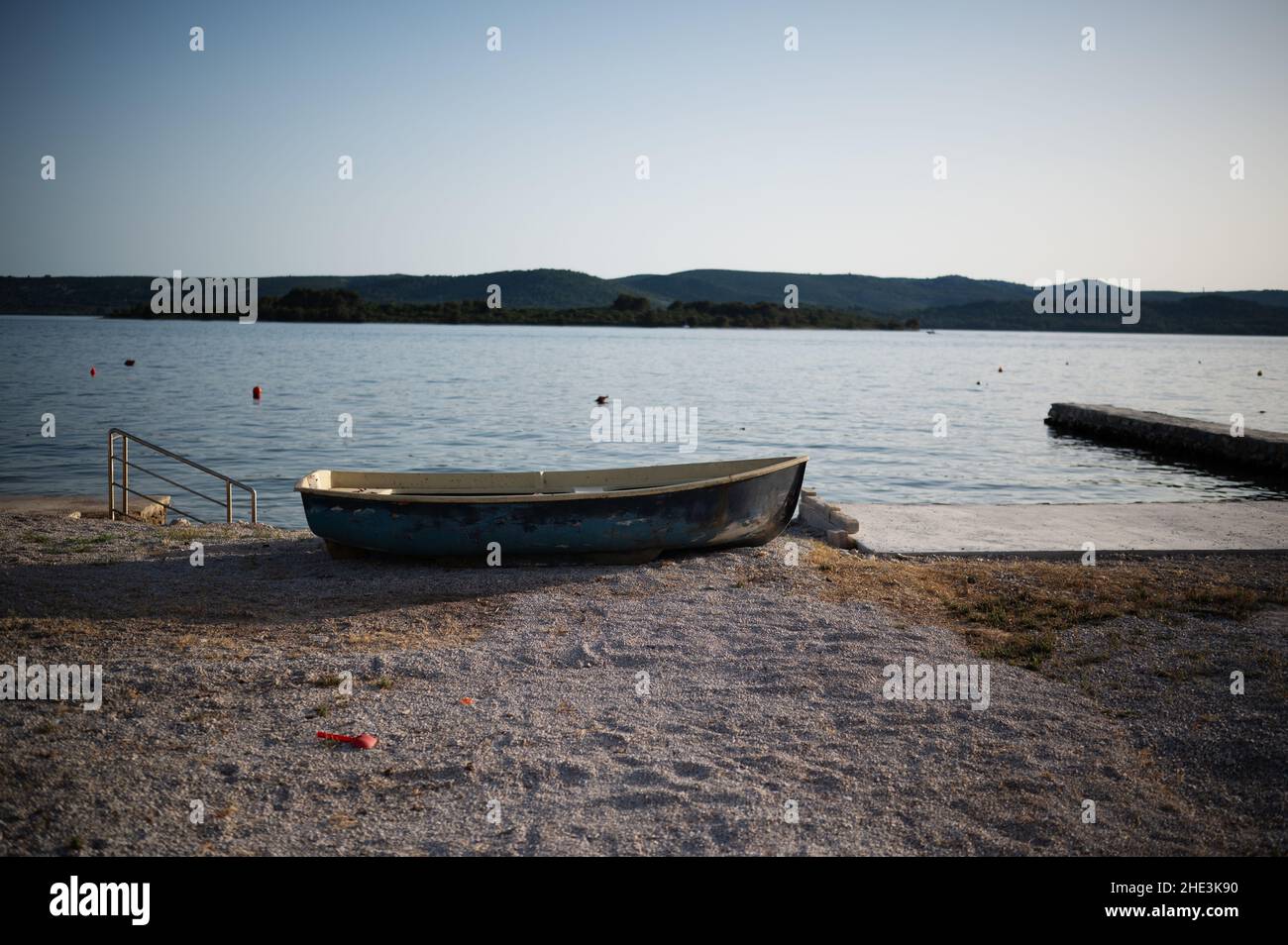 Ein kleines Ruderboot ruht bei Sonnenaufgang an einer sandigen Küste des Ozeans. Stockfoto