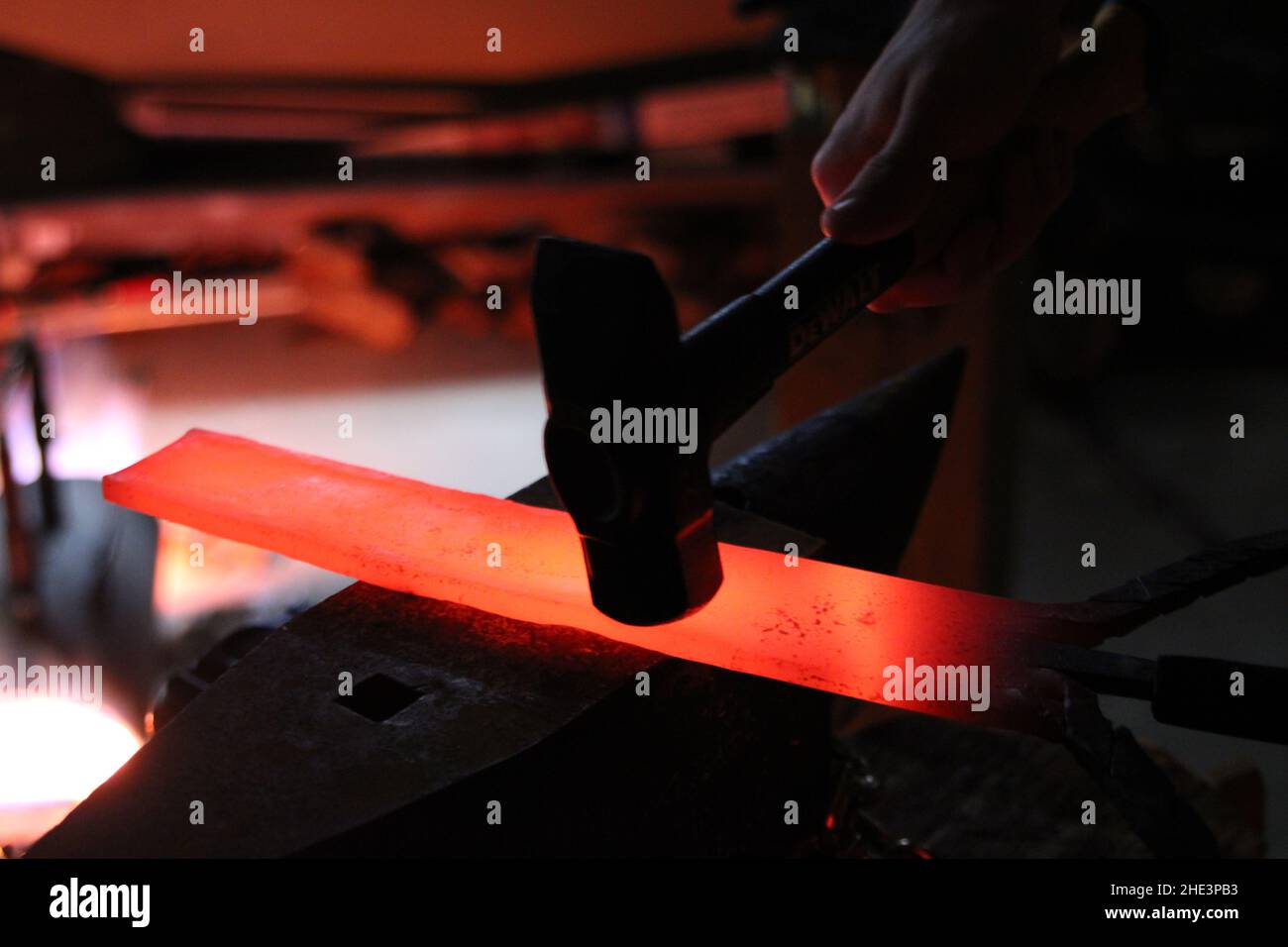 Der Schmied aus lokalem Eisenstahl erschafft einen Hammerofen, der ein Messerschwert erzeugt Stockfoto