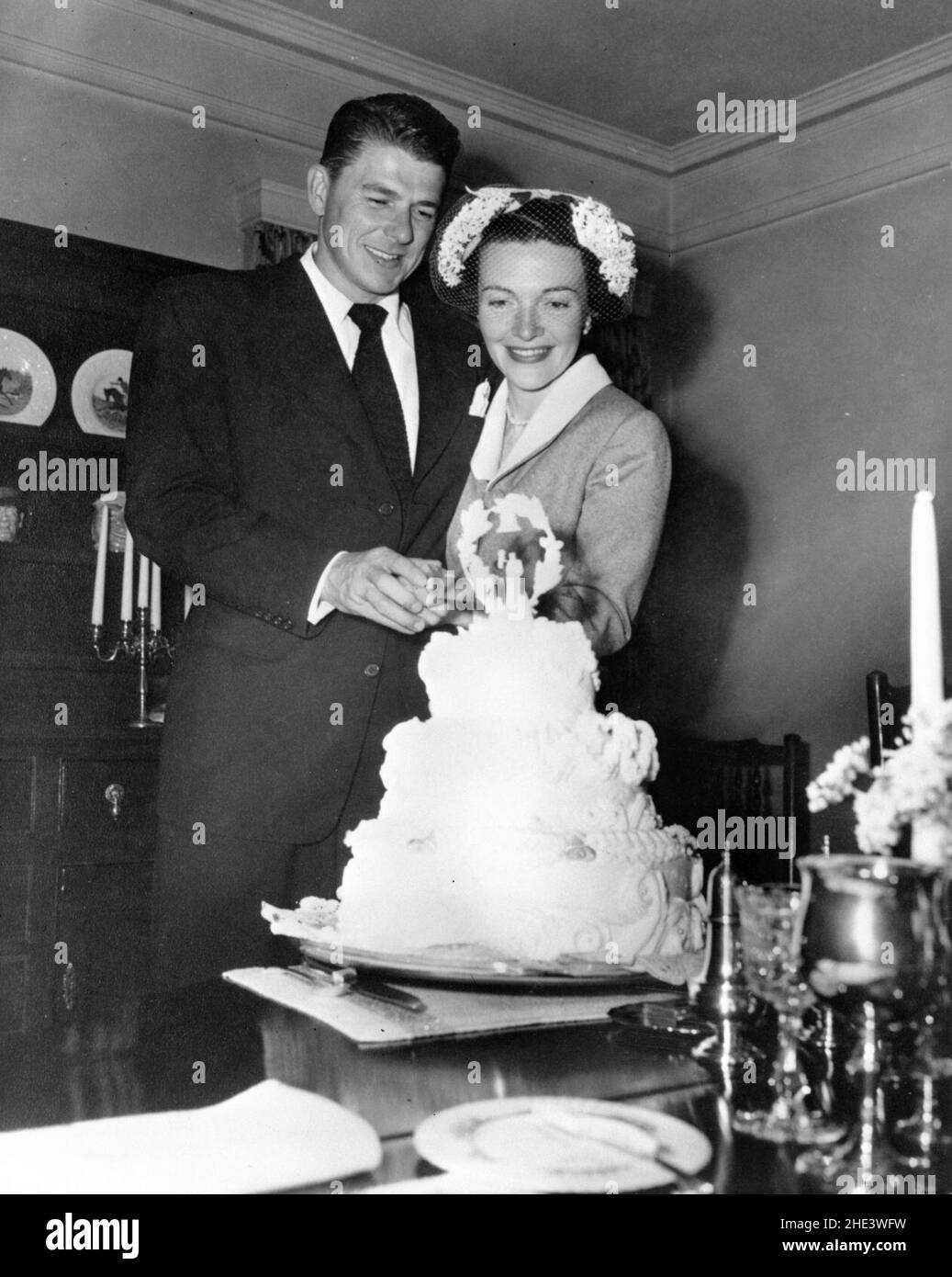 Ronald Reagan und Nancy Reagan schneiden Kuchen im Haus von William Holden nach ihrer Hochzeit in Toluca Lake, Kalifornien. Stockfoto