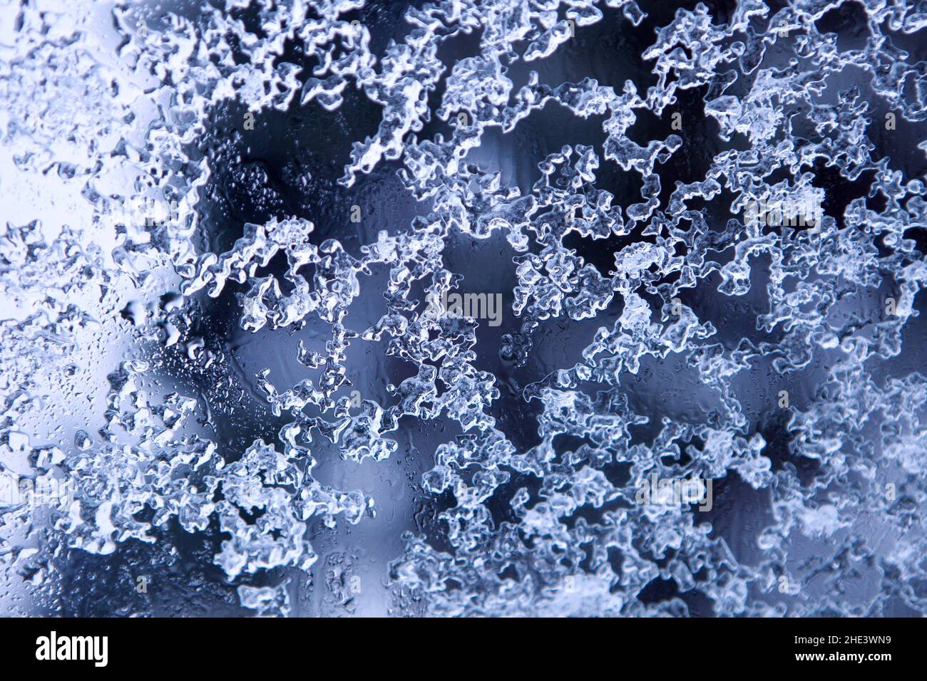 Gefrorene dekorative Wassertropfen - natürliches Wintereis Muster auf Glas. Schmelzende Schneeflocken Stockfoto