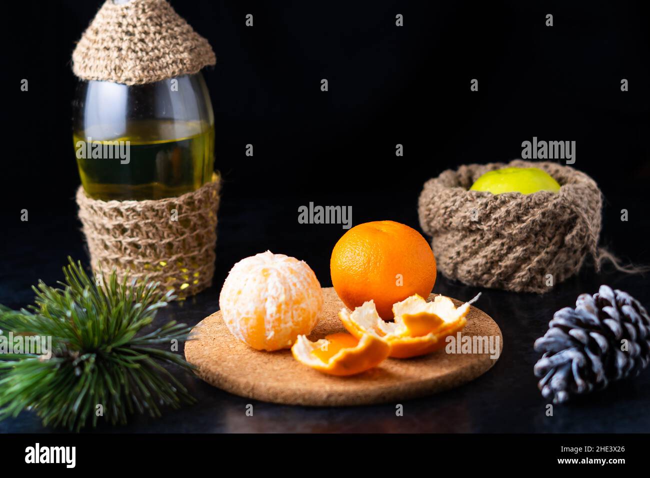 Neujahr Weihnachten Stillleben Zweig der Kiefer neben Mandarinenzapfen auf schwarzem Hintergrund Stockfoto