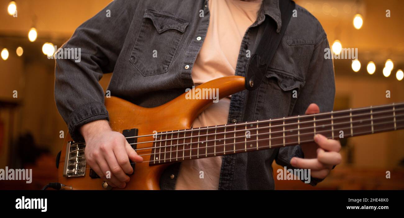 Ein junger Mann mit Bart spielt eine Bassgitarre mit fünf Saiten Stockfoto