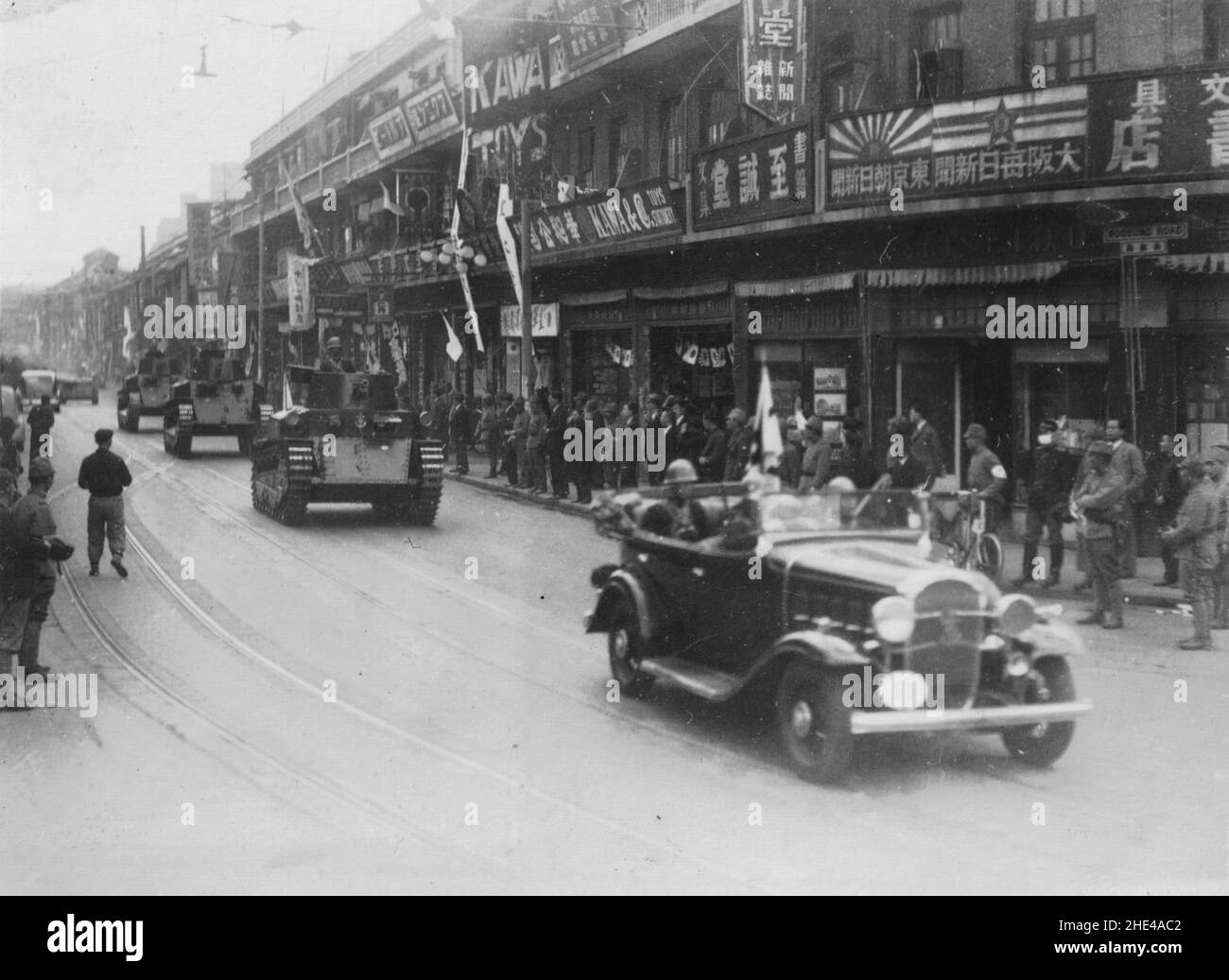 Zweiter Chinesisch-Japanischer Krieg, 1937-1945. Nach ihrem Sieg gegen die Truppen der chinesischen Nationalen Revolutionären Armee in der Stadt am 1937. Dezember patrouillieren ein japanischer Beamter der Sondermarine Landing Force, gefolgt von drei mittleren Panzern des Typs 89 und einer Carden Loyd Tankette in einer von Japan bewohnten Straße in Shanghai. Stockfoto