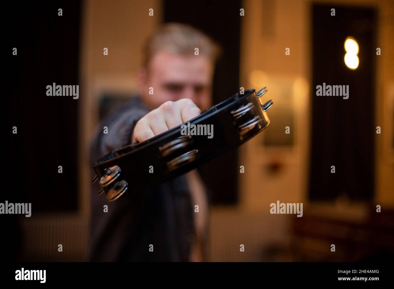 Ein junger Mann mit Bart spielt Tamburin Stockfoto