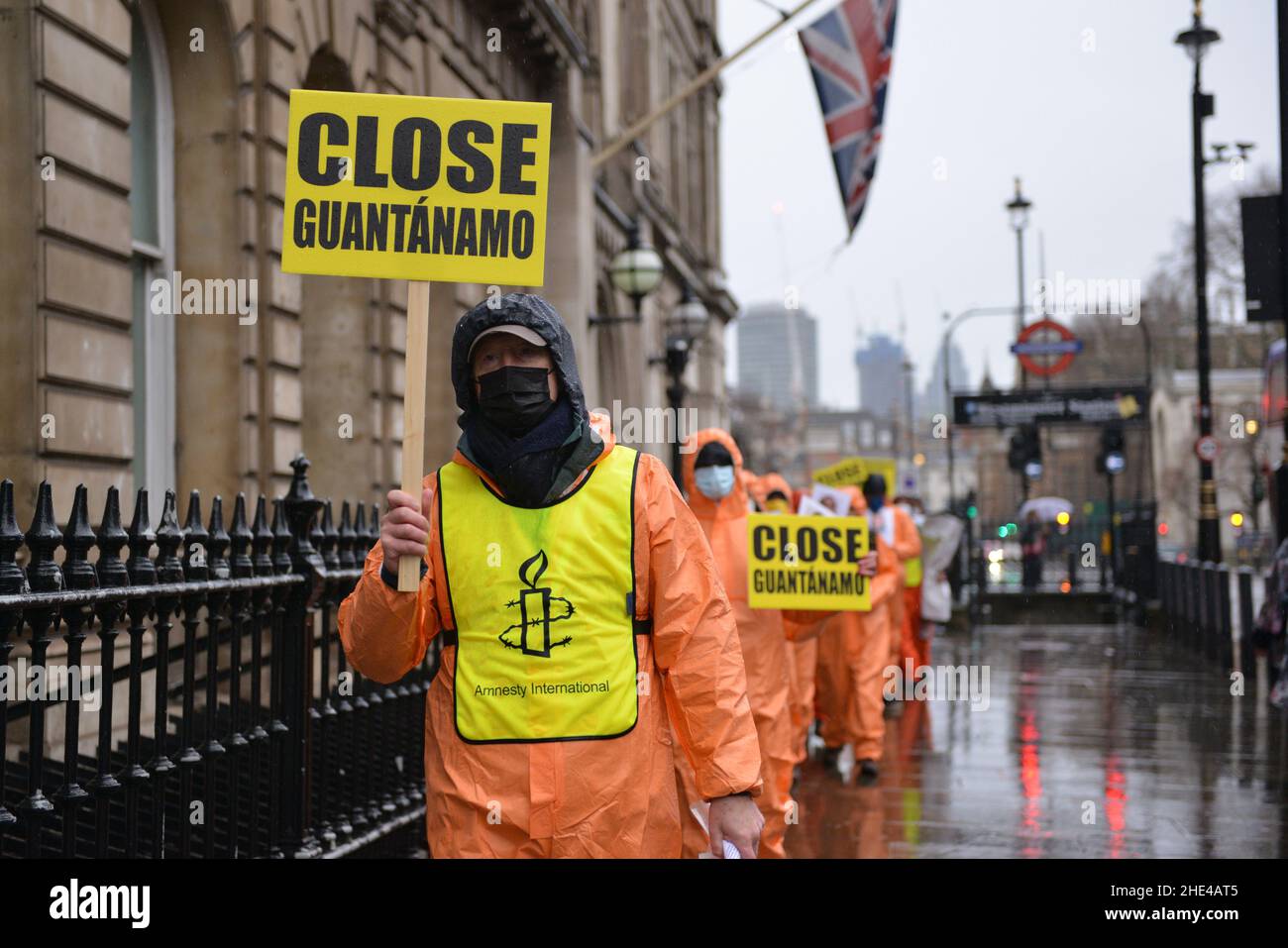 London, Großbritannien. 08th Januar 2022. Demonstranten halten während der Demonstration Plakate. Aktivisten, die in orangefarbenen Overalls und Kapuzen gekleidet waren und die 39 Männer repräsentierten, die immer noch im Gefangenenlager Guantanamo Bay festgehalten werden, marschierten aus Anlass des 20-jährigen Begehens vom Parliament Square zum Trafalgar Square. Kredit: SOPA Images Limited/Alamy Live Nachrichten Stockfoto