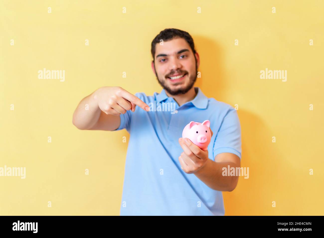Mann mit Sparschwein. Nahaufnahme des Fingers, der auf ein Sparschwein zeigt. Stockfoto