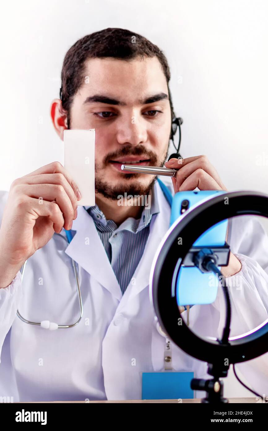 Positiver Arzt in Ohrhörern, der Online-Konsultation mit dem Patienten hat. Stockfoto