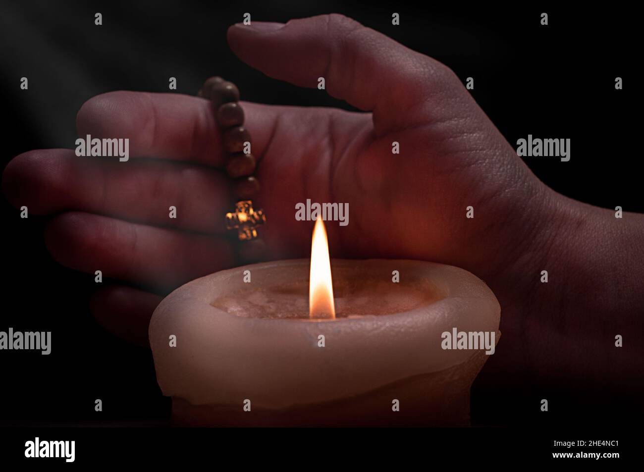 Eine brennende Kerze in der Hand in der Dunkelheit Stockfoto