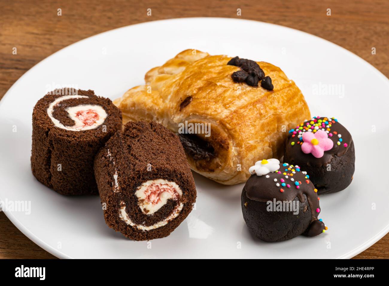 High-Angle-Ansicht von verschiedenen Dessert in weißen Keramikschale. Sortiment Dessert, Schwarzwälder Biskuitrolle, Dänisches Gebäck gefüllt mit Schokoladencreme Stockfoto