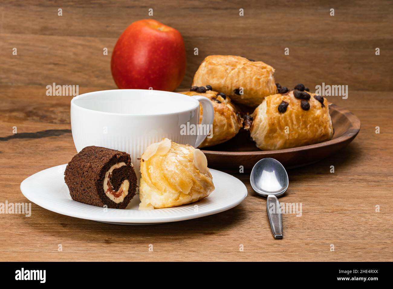 Köstliche Kaffeepause mit verschiedenen Dessert in weißen Keramikschale mit einer Tasse Kaffee und rot reifen Apfel. Köstliches hausgemachtes Dessert, Mini Black Fore Stockfoto