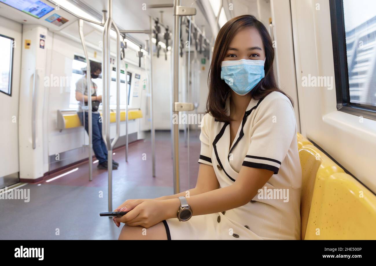 asiatische Frau mit medizinischer Maske auf öffentlichen Verkehrsmitteln und halten mehr Abstand von einem anderen in Sicherheit Pandemie-Konzept Stockfoto