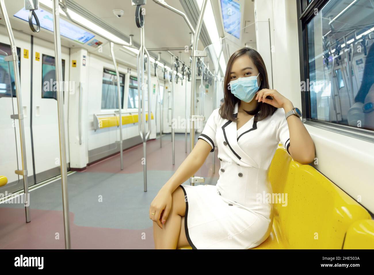 Asiatische Frau, die in der Ära des Coronavirus medizinische Masken auf einem leeren Passagier im öffentlichen Skytrain trug Stockfoto