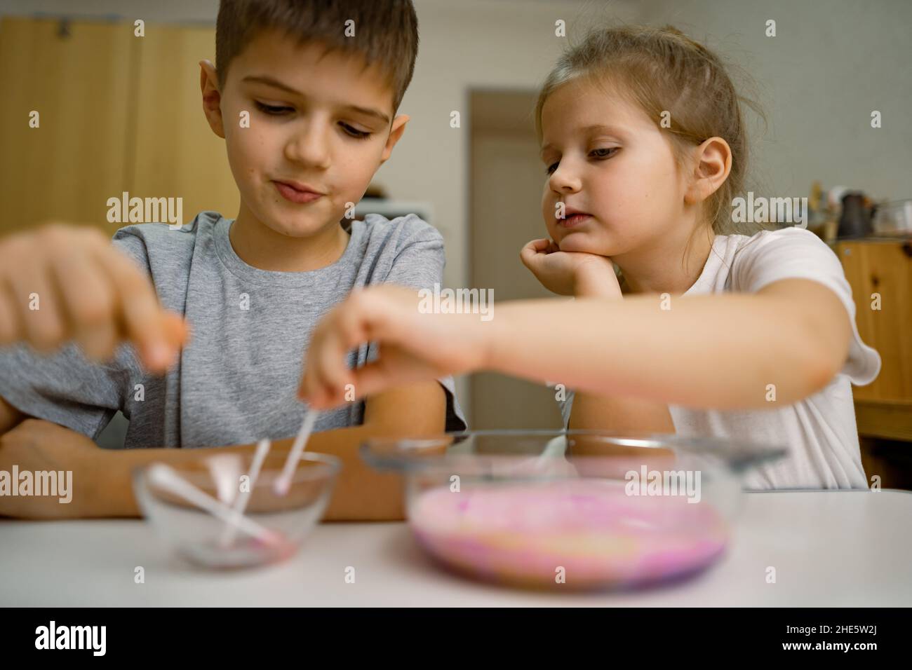 Kinder, Mädchen, Junge zu Hause, experimentieren mit Milch und Farben Stockfoto