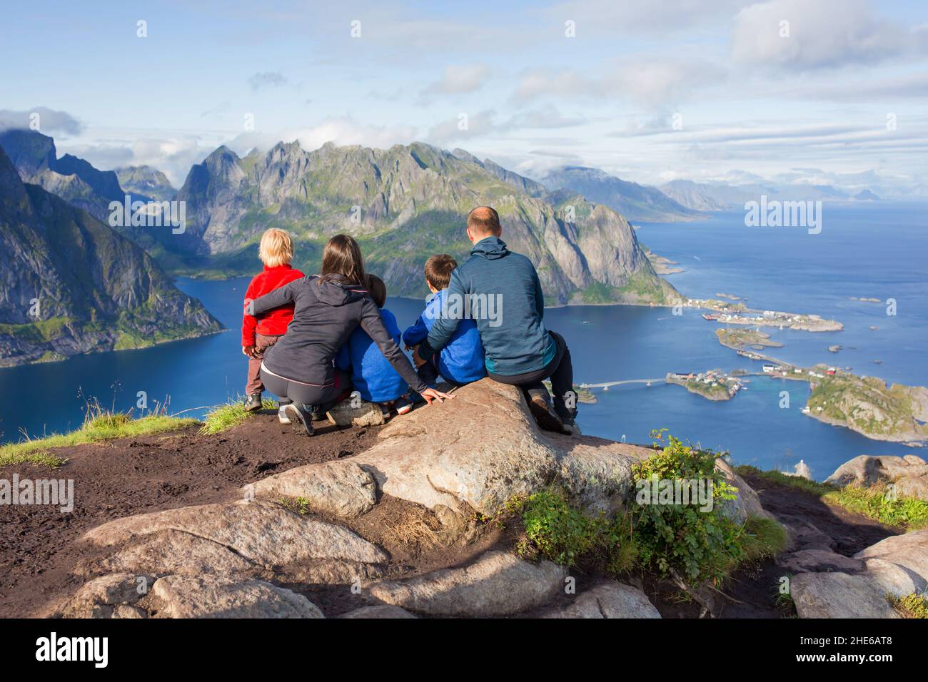 Familie, die auf den Bergen sitzt und nach dem Aufstieg auf den Reinebringen Baumweg mit vielen Treppen, Lofoten, nördliches Nor, auf reine herabblickt Stockfoto