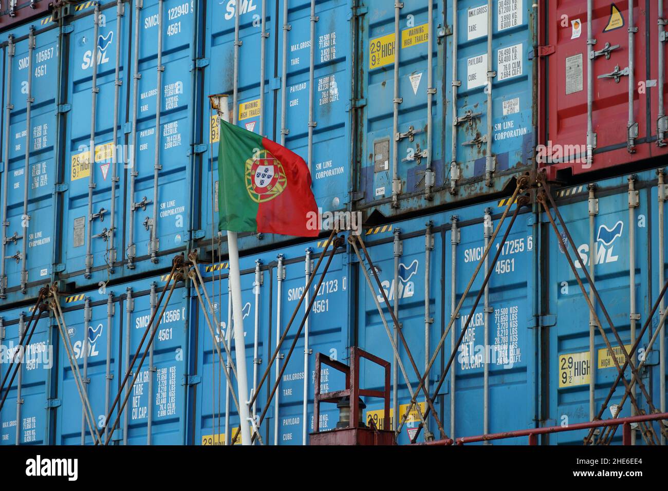Flagge Portugals auf weißem Mast, der sich im hinteren oder hinteren Teil des Containerschiffes befindet. Stockfoto