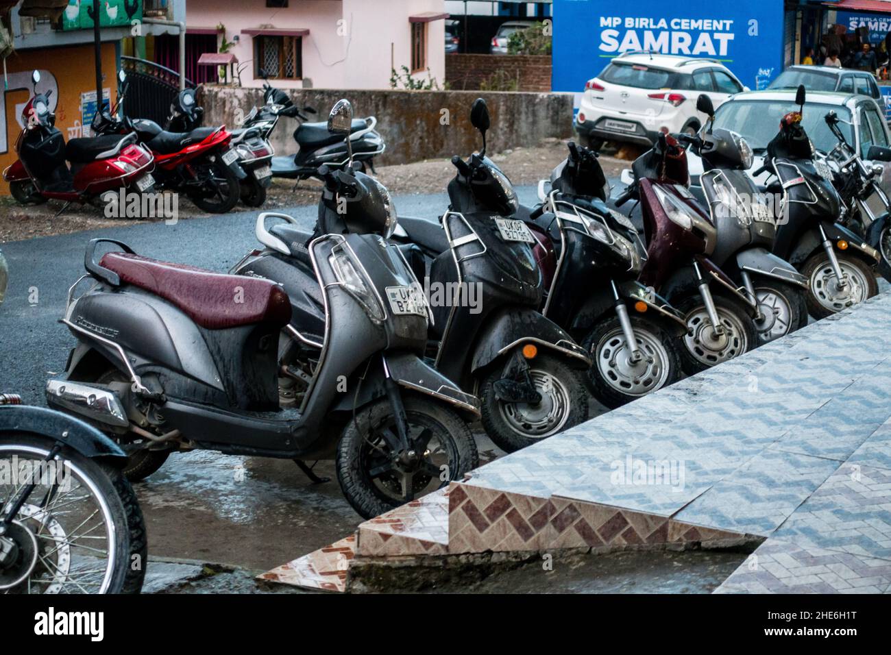 Editorial vom:27th Feb '2021 Ort: Dehradun, INDIEN. Zweiräder parkten bei Regen auf einem Fußweg. Stockfoto