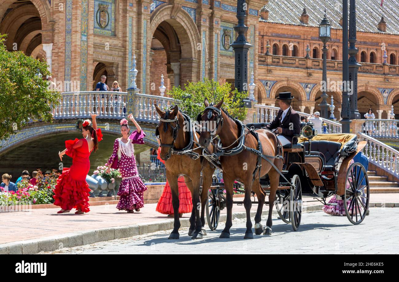 Damen in traditionellen Flamenco-Kostümen tanzen auf der Plaza de Espana, während ihre Pferdekutsche sie zur jährlichen Feria de Abril bringt. Stockfoto