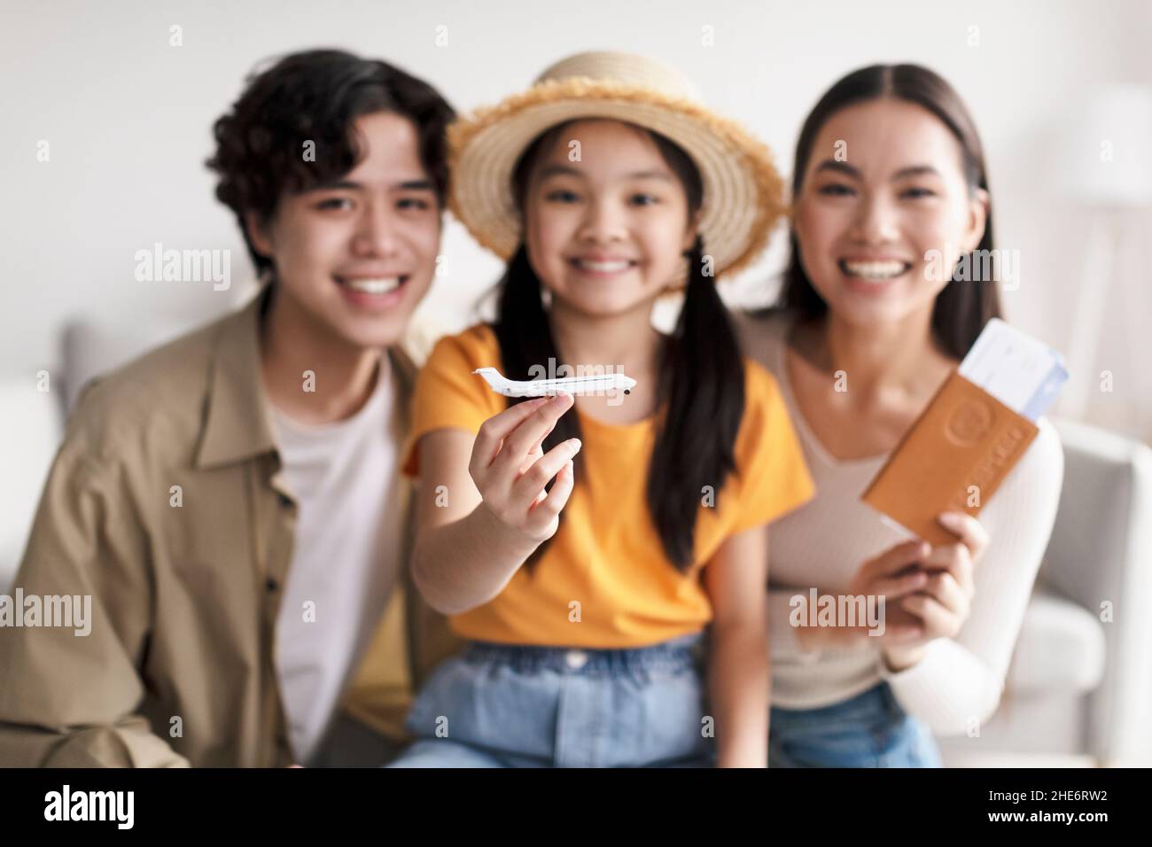 Lächelndes junges Mädchen im Huthalteflugzeug, selektiver Fokus. Millennial japanischen Eltern glücklich und zeigen Pass und Tickets Stockfoto