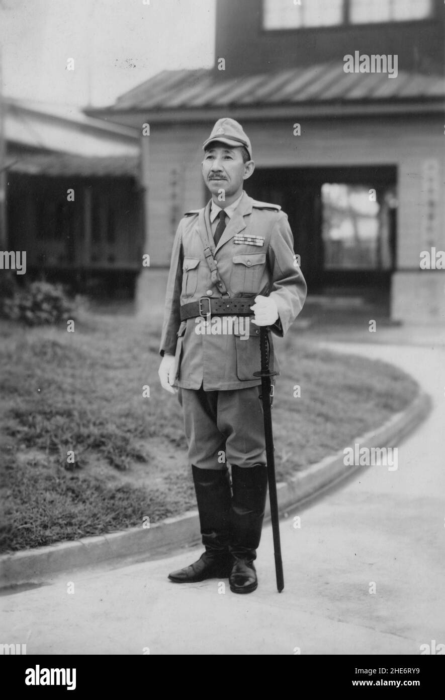 Zweiter Chinesisch-Japanischer Krieg, 1937-1945. Konteradmiral Yamazaki Sukichi, Kommandant der 15th Verteidigungs-/Wacheinheit, steht mit seinem Schwert vor dem Hauptquartier der Einheit auf der nordöstlichen Insel Hainan, um 1942. Die kaiserliche japanische Armee und die Marine starteten im Februar 1939 eine gemeinsame Gefangenenoperation der Insel Hainan, wobei letztere auf der Insel weiterhin aroniert blieb und an einer Reihe von Aufräumoperationen gegen den lokalen Widerstand bis zum Abschluss des Zweiten Chinesisch-Japanischen Krieges teilnahm. Stockfoto