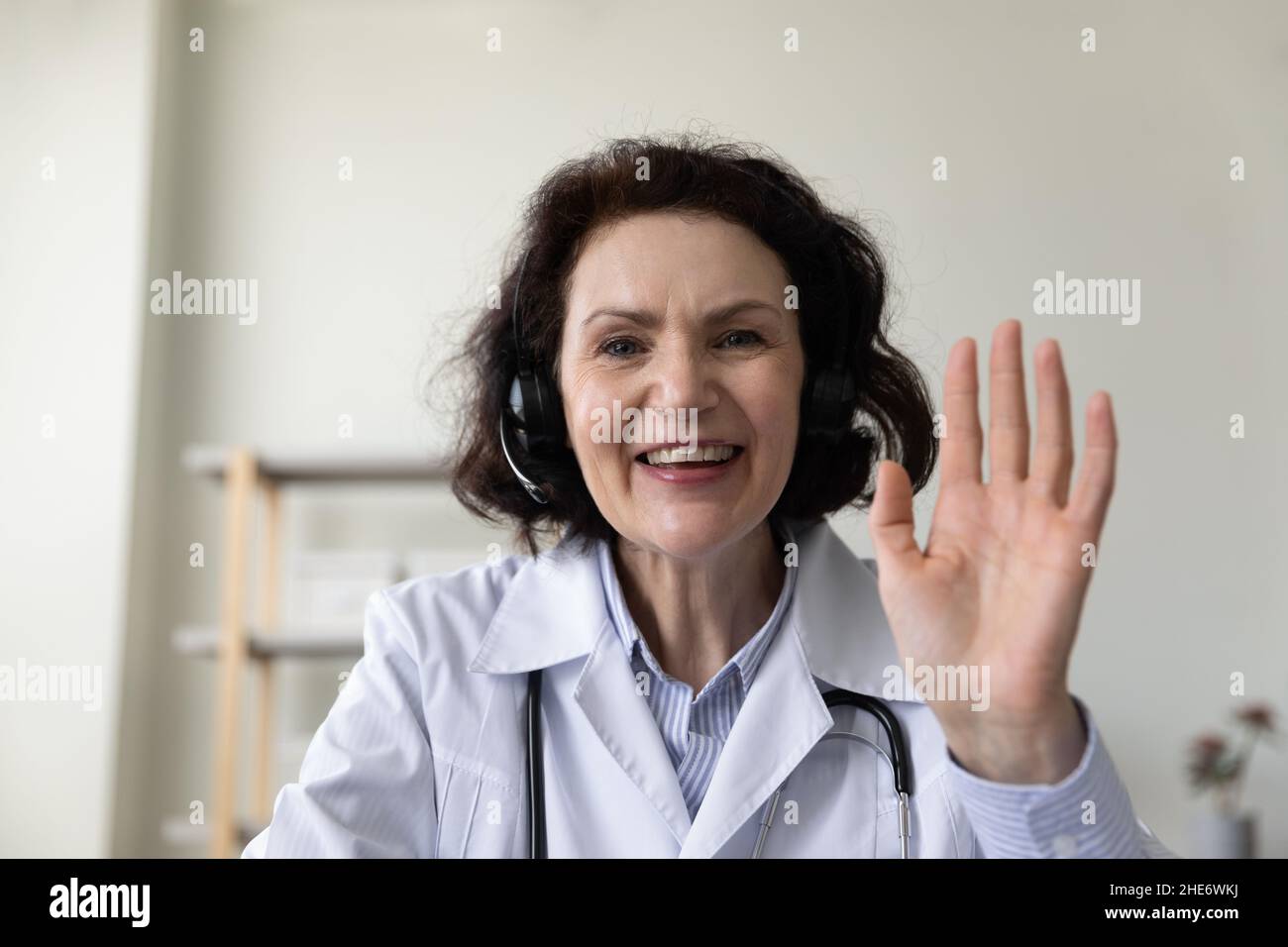 Lächelnde Ärztin mittleren Alters mit Videoanruf. Stockfoto