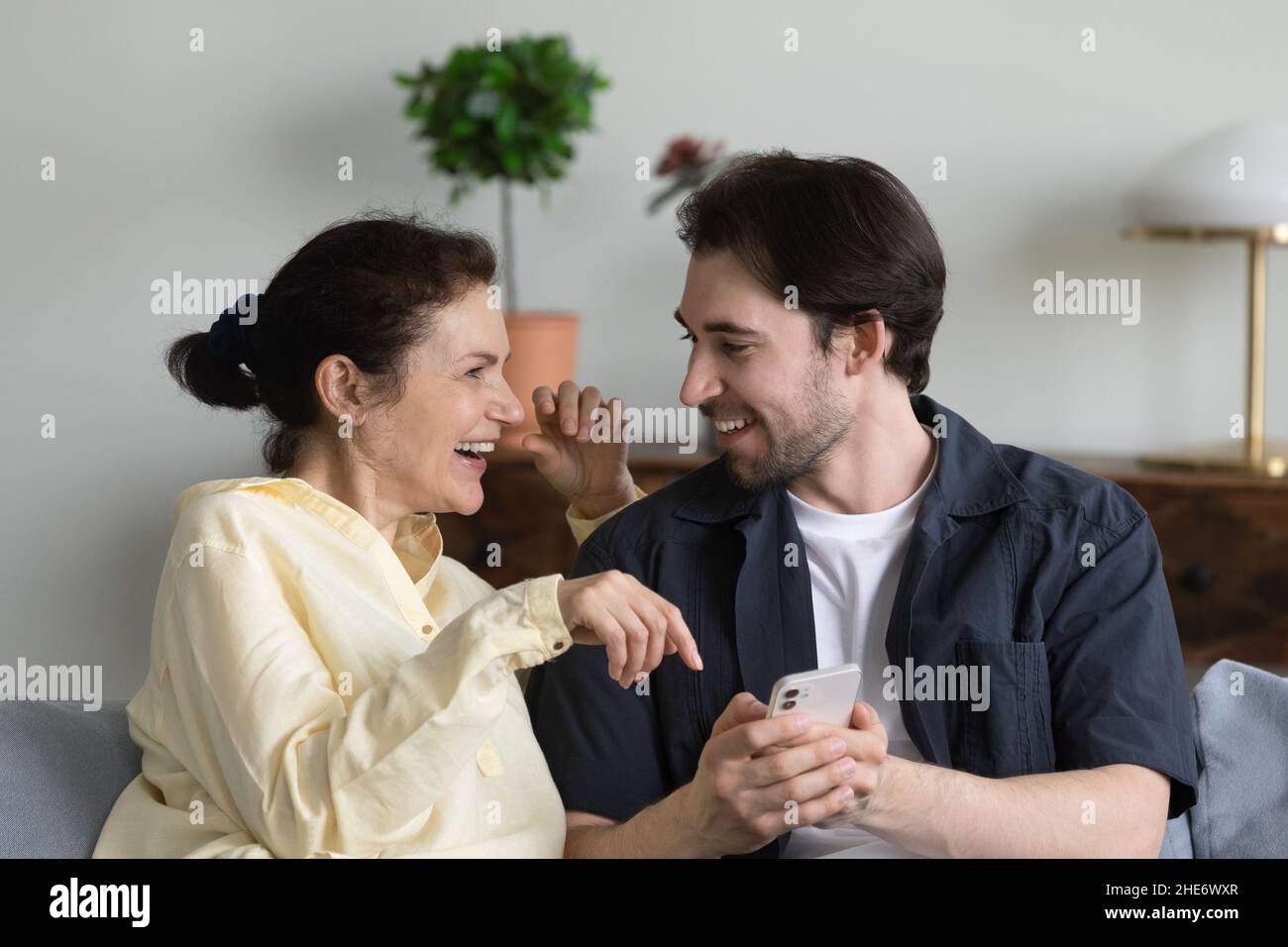 Glücklicher junger Mann, der Handy mit reifer Mutter benutzt. Stockfoto