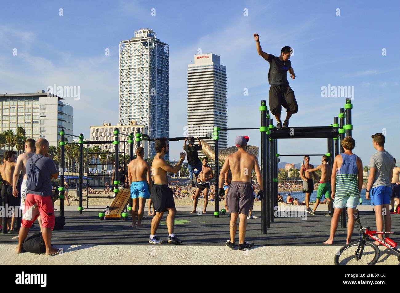 Männer trainieren am Strand von Port Olimpic mit Torre Mapfre und den berühmten Wolkenkratzern im Hintergrund von Hotel Arts, Barcelona Spanien. Stockfoto