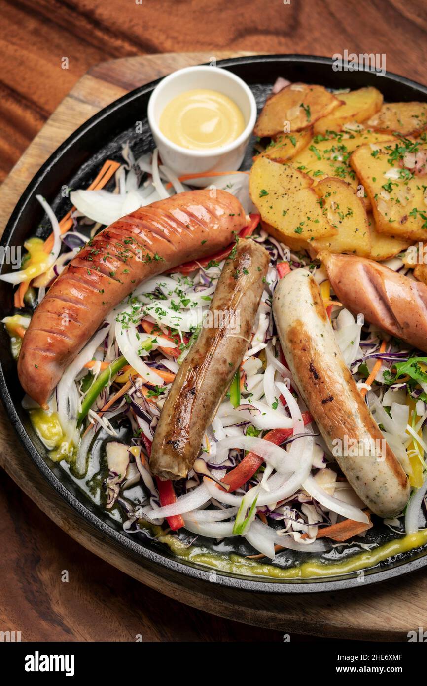 Gemischte deutsche traditionelle Bio-Wurst- und Kartoffelmahlplatte mit Nurenberger, Lamm und Schweinefleisch mit Salat und Senf Stockfoto