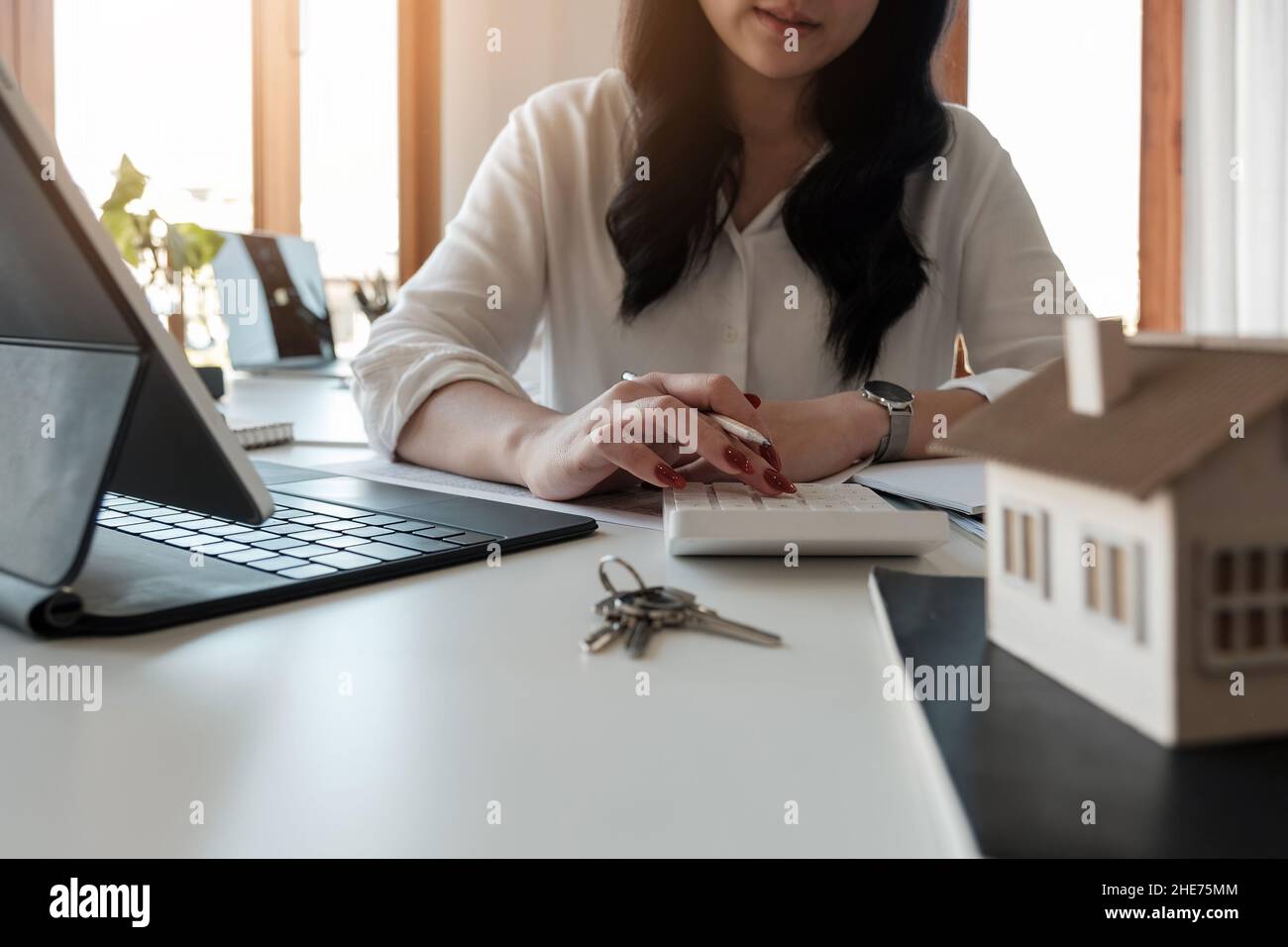 Close up Hand of Business Asian Woman mit der Berechnung von Zinsen, Steuern und Gewinnen in Immobilien und Hauskauf zu investieren. Stockfoto