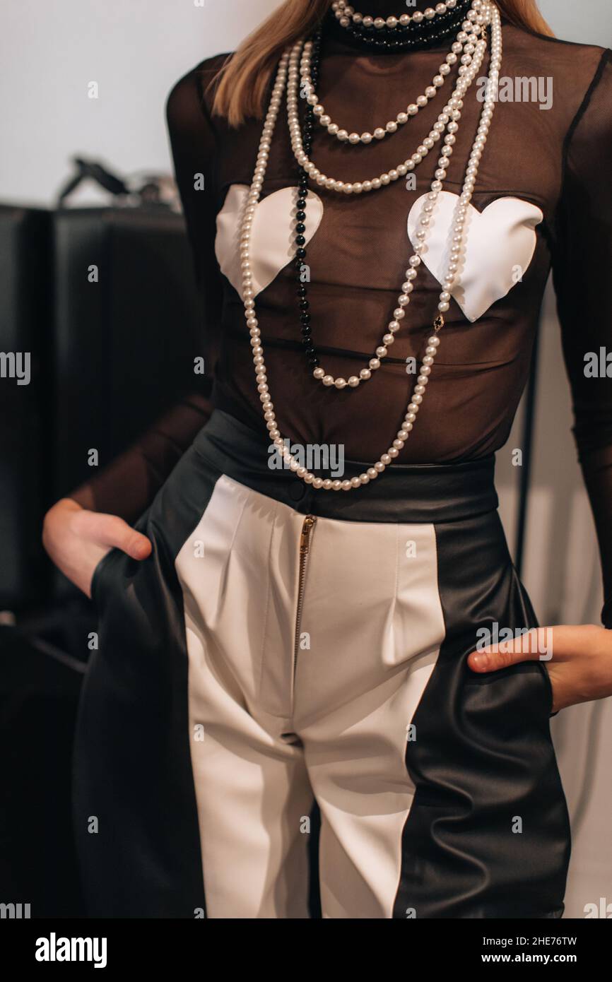Verkürzte Figur der Modelfrau trägt kreative Top mit Herzen, schwarz-weiße Hose mit Reißverschluss und Perlen. Mode stilvolle weibliche Gerinnsel Stockfoto