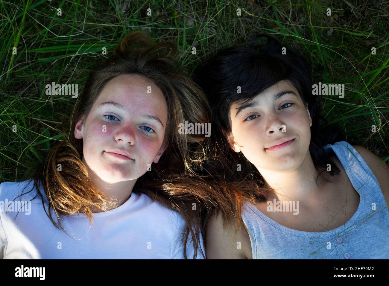 Porträt von zwei Teenager-Mädchen auf Gras liegen und gute Zeit haben. Stockfoto