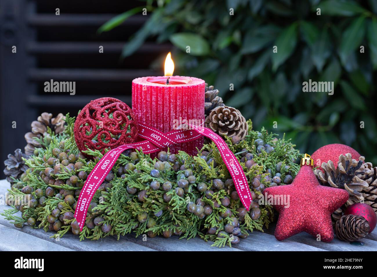 weihnachtsdekoration mit roter Kerze und Kranz aus Wacholderbeeren Stockfoto